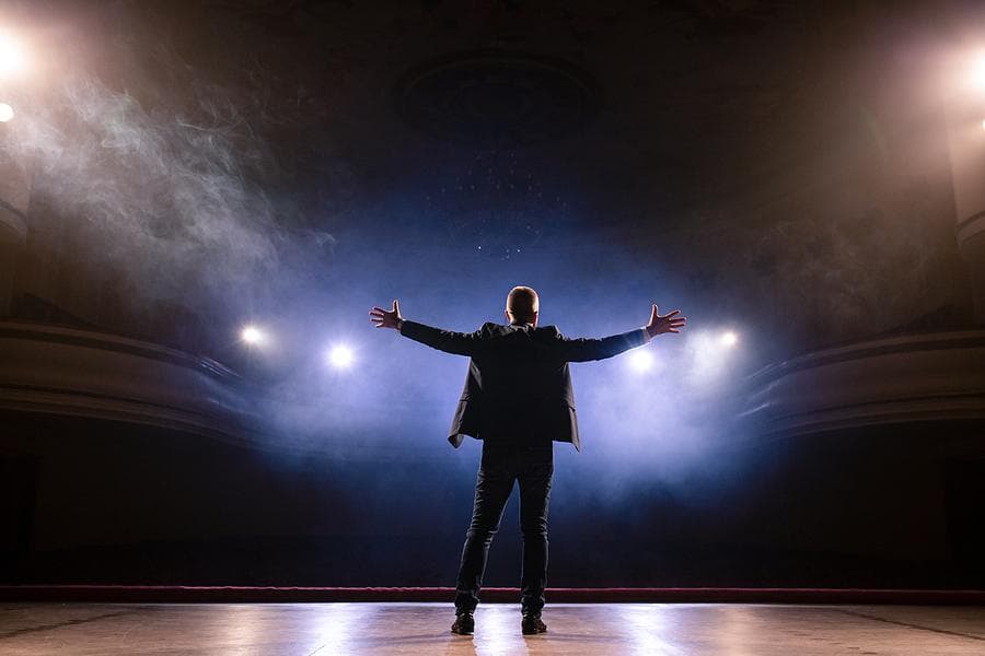 A speaker on stage under spotlights